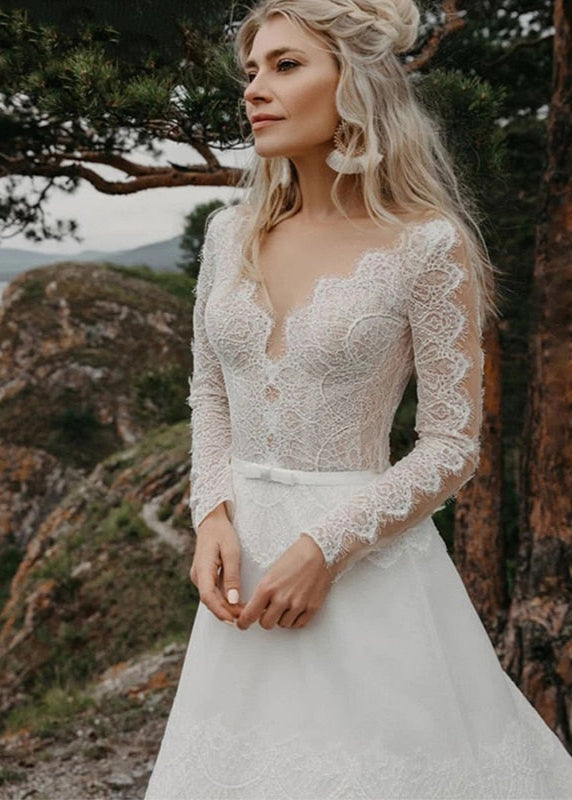 Introducing the Robe Elize, a sophisticated and elegant bridal dress perfect for your beach bohemian wedding. Featuring beautiful lace applique, a transparent long sleeve design, and a chic V-neckline, this plus size dress will make you feel like a ethereal goddess on your special day.