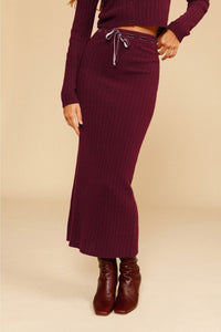 Indulge in luxury and comfort with our Ensemble Cirielle. This stylish two-piece set features a deep V rib long sleeve sweater and a midi ribbed knit skirt, both in a vintage burgundy color. The ribbed crop cardigan adds a sophisticated touch with a sexy V neckline and bow tie detail. Perfect for the upcoming seasons, complete the look with chunky boots and a classic baguette bag.