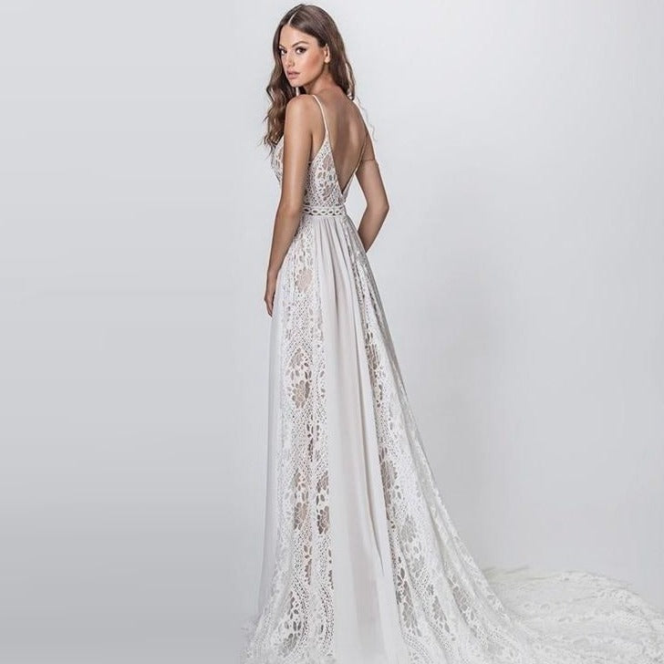 A-line wedding gown with spaghetti straps. The bodice features a nude lining with a beaded crochet lace overlay embellished with crystals and pearls, and open sides with two tassels on each side. Skirt is made of chiffon and lace for the ultimate elegant bohemian look.