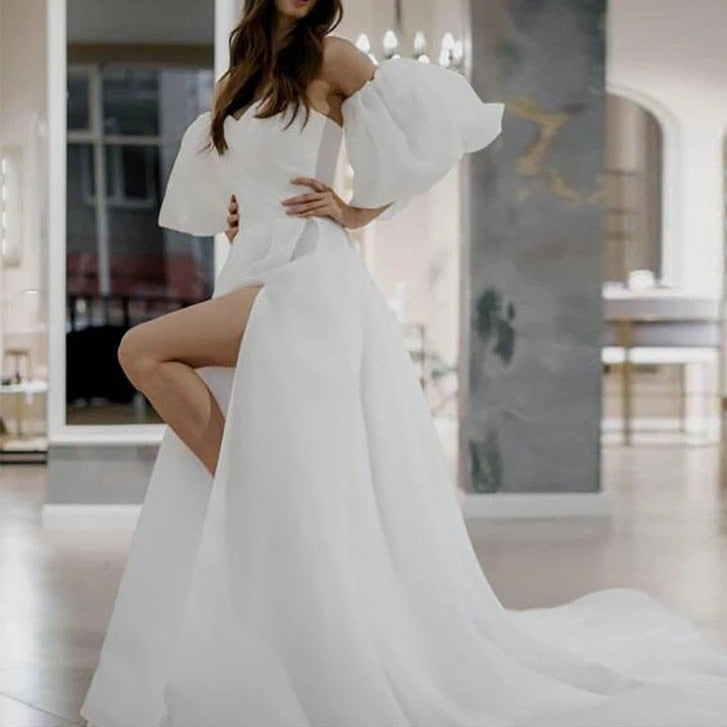 Indulge in elegance with our Robe Ileanna. This beautiful white bridal dress boasts puff sleeves and a simple yet stunning design. Perfect for your special day, the delicate details evoke a sense of timeless beauty and sophistication. Say "I do" in style with this luxurious piece.