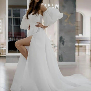 Indulge in elegance with our Robe Ileanna. This beautiful white bridal dress boasts puff sleeves and a simple yet stunning design. Perfect for your special day, the delicate details evoke a sense of timeless beauty and sophistication. Say "I do" in style with this luxurious piece.