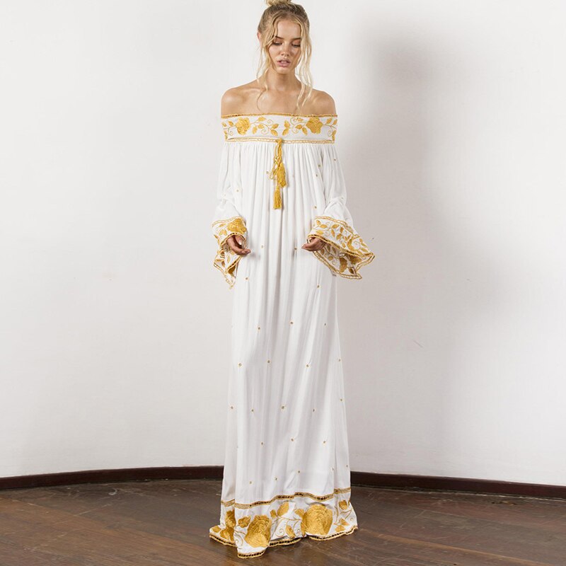 Introducing the elegant and stylish Robe Jenna. Made from soft, breathable cotton, this long dress features delicate floral embroidery and trendy tassels. With its off-the-shoulder design and bohemian flair, it's perfect for beach and summer wear. Upgrade your wardrobe with this must-have piece.