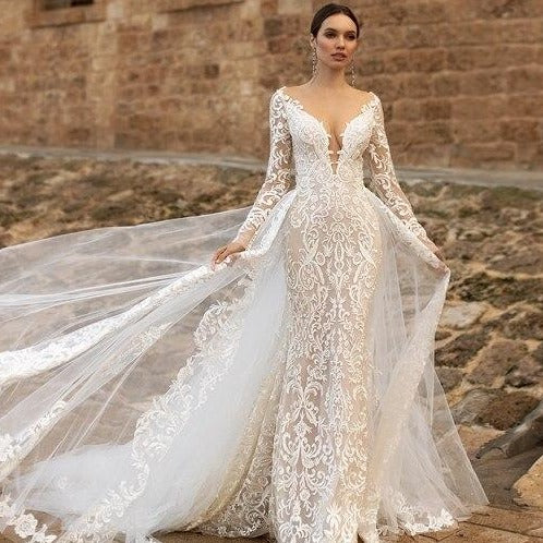 Looking for an elegant look for your bridal day? The Robe Michaelina has got you covered! This sophisticated chic bridal dress features a gorgeous lace gown and a unique lace cape, perfect for a one-of-a-kind bridal look. Say yes to this dress and stand out on your special day!