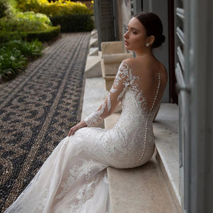 Indulge in the luxury of the Robe Neila. With its elegant lace design, this bridal gown exudes sophistication and chic style. The open back and siren mermaid silhouette add a sexy touch, making you feel like a true siren on your special day. Elevate your bridal look with this exclusive piece.