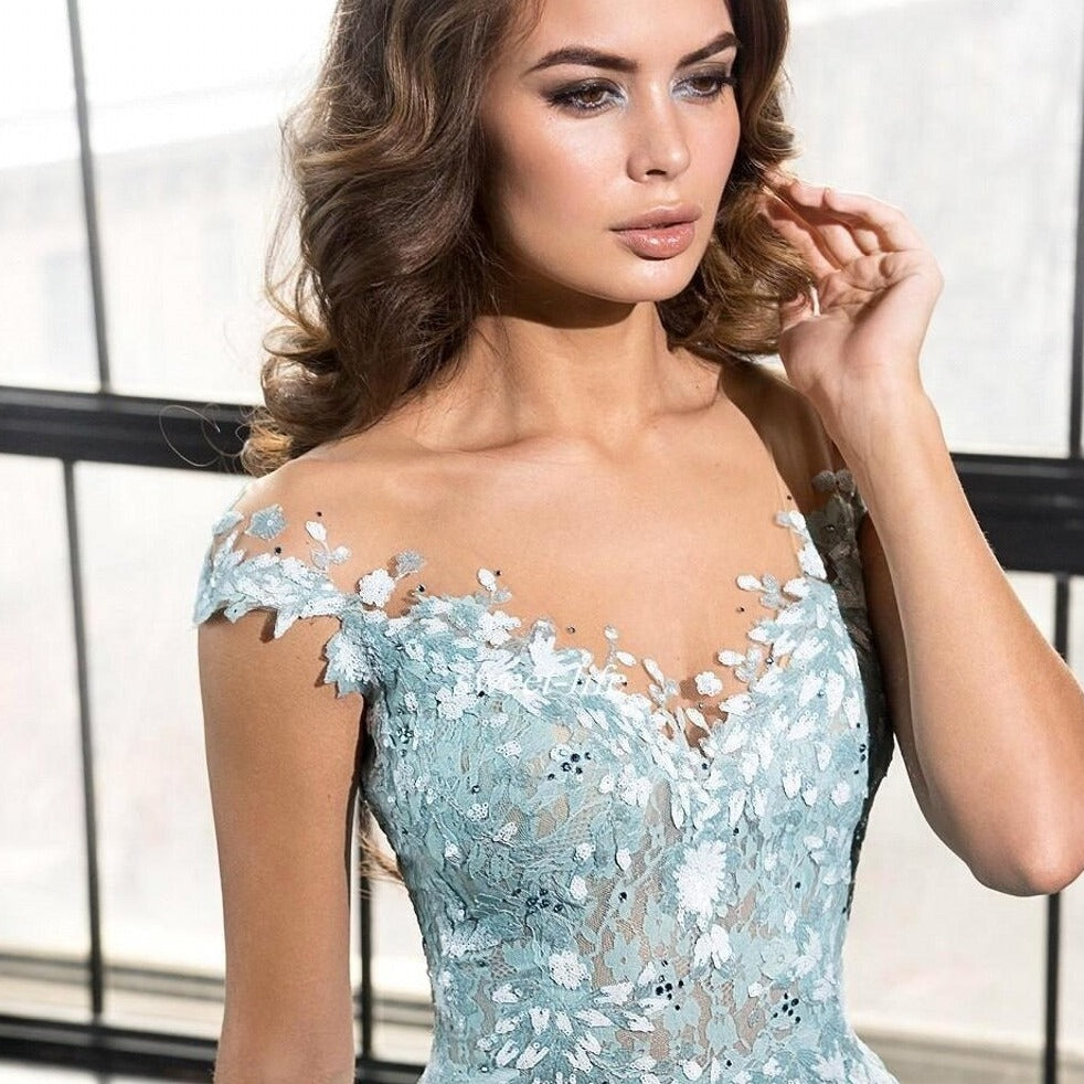 Expertly crafted with intricate blue illusion lace and beaded appliques, the Robe Marigold is a stunning prom dress for a luxurious evening. The flowing court train adds an elegant touch while showcasing your figure. Make a statement in this long, glamorous gown.