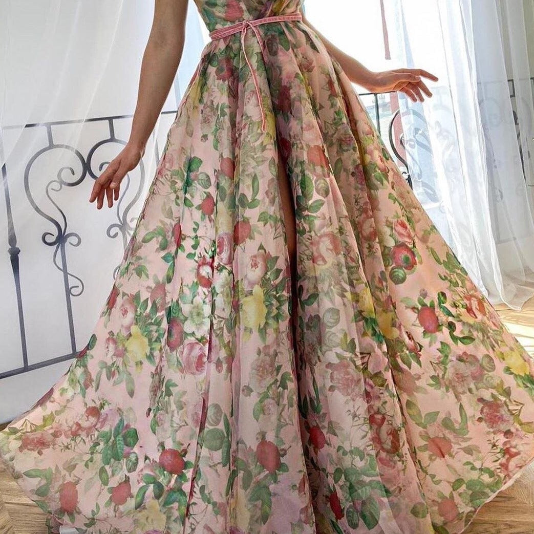 Experience the beauty of a flower field with our Dreamy Scarlet Gown. Made from printed organza, this gown features delicate handmade embroidered blooms along the shoulder straps. A luxurious velvet belt defines the waist, creating a flattering silhouette. Let this gown transport you to a dreamy garden, wherever you may go.