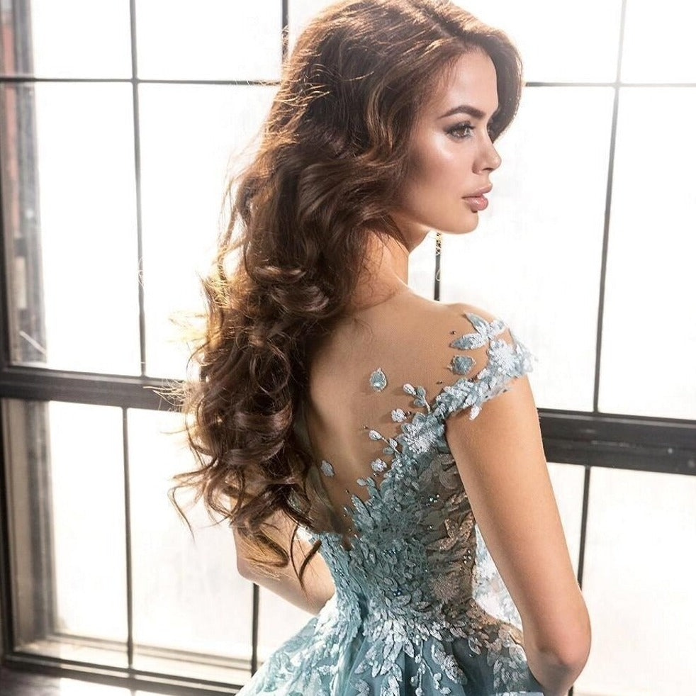 Expertly crafted with intricate blue illusion lace and beaded appliques, the Robe Marigold is a stunning prom dress for a luxurious evening. The flowing court train adds an elegant touch while showcasing your figure. Make a statement in this long, glamorous gown.