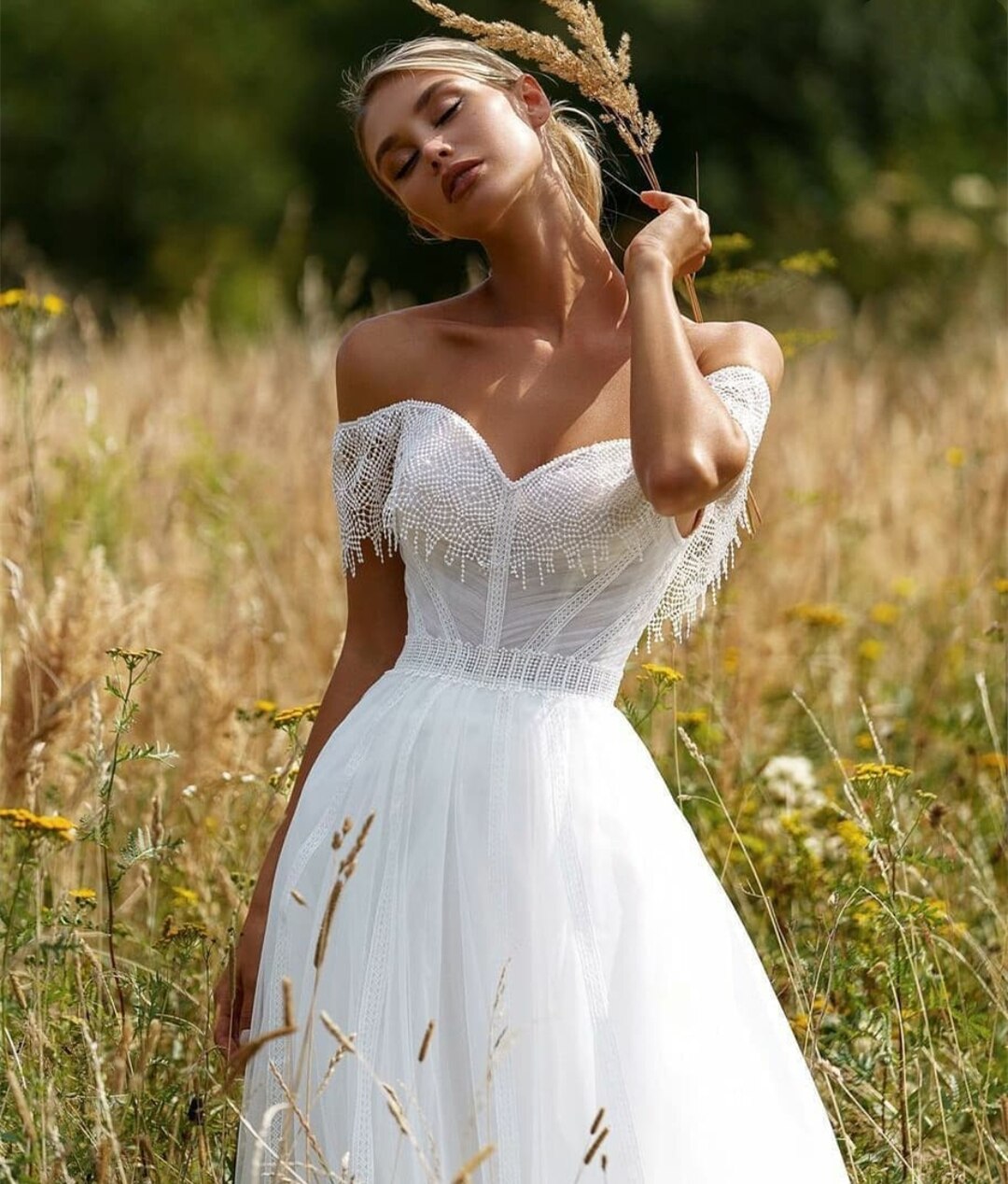 "Unleash your inner boho beauty with our Robe Franchele! This stunning A-line wedding dress features a sweetheart neckline, open back, and delicate embroidery lace. Complete with fringe arm bands for a touch of whimsy. Let your free-spirited style shine on your special day!"