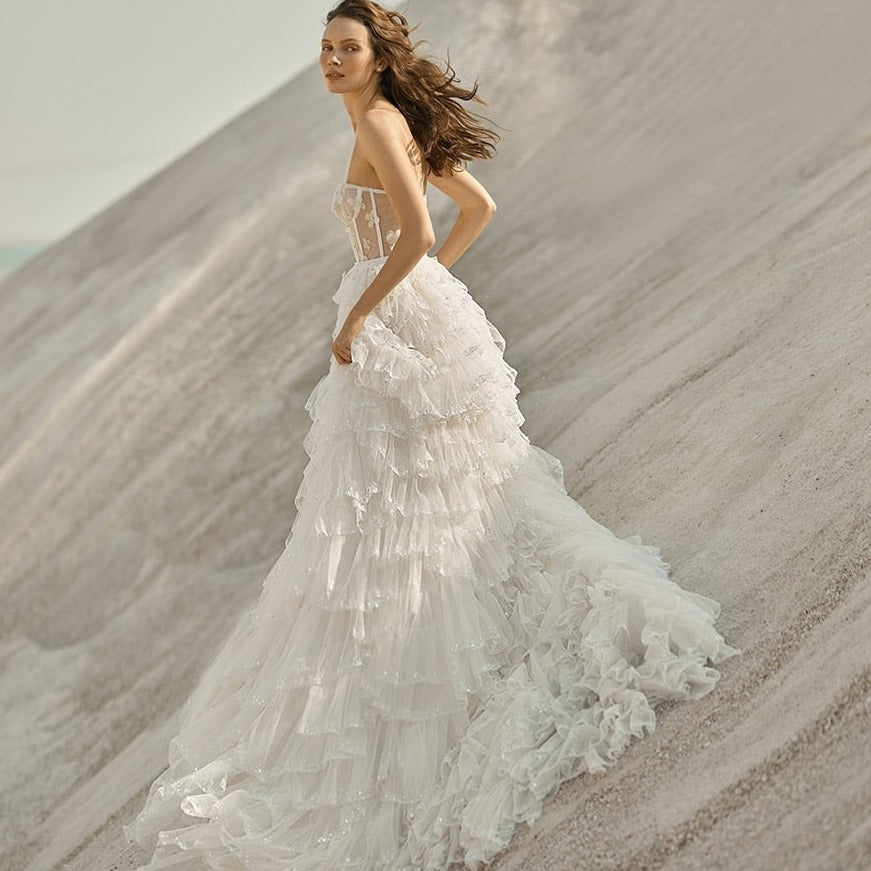 This elegant ruffle wedding gown, Robe Agne, exudes sophisticated charm and timeless beauty. The delicate ruffles add a touch of romance while flattering the figure. Made for the modern bride, this gown is a perfect blend of style and grace.