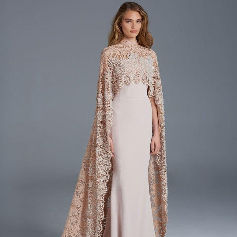 The Robe Joule is the ultimate evening gown for sophisticated events. Its mermaid silhouette flatters your figure, while the high neck and sheer lace cape add a touch of elegance. Perfect for parties, it's sure to turn heads with its timeless design.