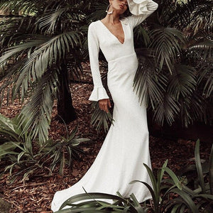 Introducing the Robe Sonyah, a luxurious and sophisticated white bridal dress. With a stunning open back, elegant long sleeves, and a flattering mermaid silhouette, this dress is the epitome of understated elegance. Perfect for the modern bride seeking a simple yet striking look on her special day.