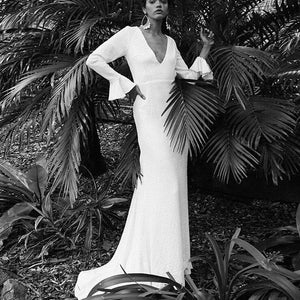 Introducing the Robe Sonyah, a luxurious and sophisticated white bridal dress. With a stunning open back, elegant long sleeves, and a flattering mermaid silhouette, this dress is the epitome of understated elegance. Perfect for the modern bride seeking a simple yet striking look on her special day.