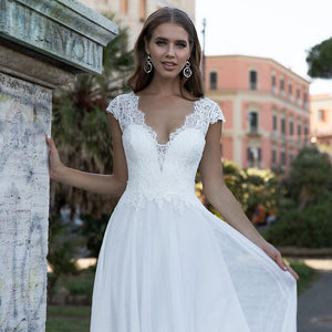 Elevate your wedding day look with the elegant Robe Maëlle. Designed in a classic white hue, this gown exudes timeless beauty. Look and feel like a vision in this stunning piece, perfect for making a lasting impression on your special day.