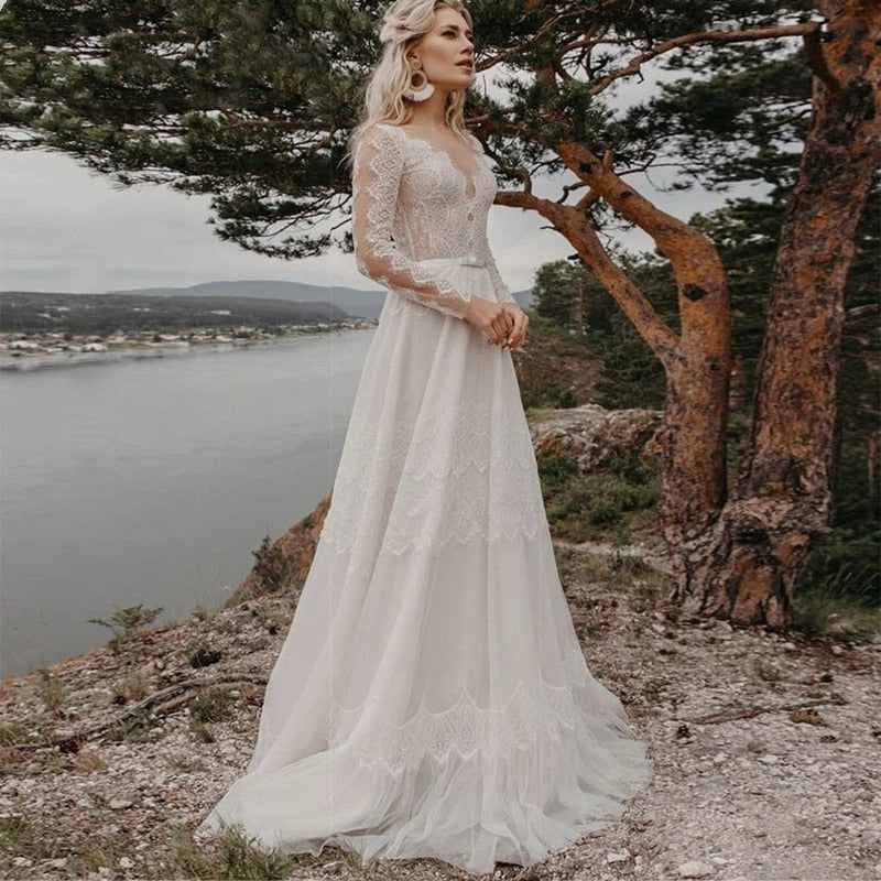 Introducing the Robe Elize, a sophisticated and elegant bridal dress perfect for your beach bohemian wedding. Featuring beautiful lace applique, a transparent long sleeve design, and a chic V-neckline, this plus size dress will make you feel like a ethereal goddess on your special day.