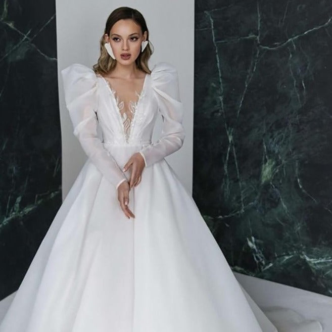 Introducing the exquisite Robe Harleigh, a showstopper among bridal gowns. Its elegant design boasts long sleeves, a chic V-neck, and exquisite embroidery. Embody sophistication and grace on your special day with this luxurious robe.