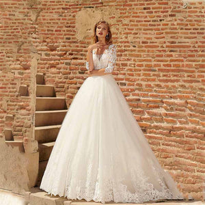 The Robe Libby is a stunning wedding dress featuring mid-length sleeves, a unique button-up back design, and intricate lace appliques. With its floor-length design, this dress is perfect for a modern yet elegant wedding look. Feel confident and beautiful on your special day with the Robe Libby.