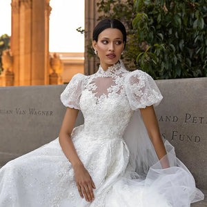 Introducing the Robe Riah - a stunning wedding dress with puff sleeves and a sparkling princess cut design. This luxurious garment exudes elegance and sophistication, making any bride feel like royalty on her special day. Experience the ultimate in bridal couture with the Robe Riah.