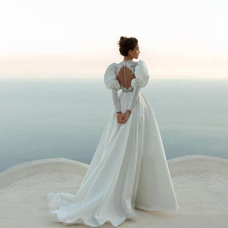 This elegant robe de marié features a trapeze silhouette, round neckline, puffy sleeves and button closures. Crafted with an exquisite length, the Robe Solei will make you the picture-perfect bride.