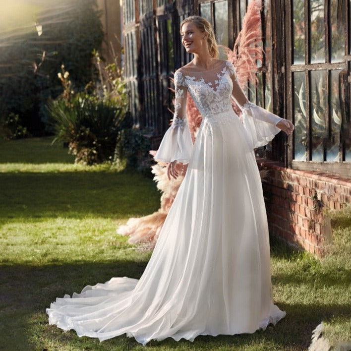 Experience the thrill and elegance of our Robe Henrietta! This trapeze-style wedding dress features a round neckline, floor-length hem, and gorgeous bishop sleeves. Walk down the aisle with confidence and grace in this stunning design.