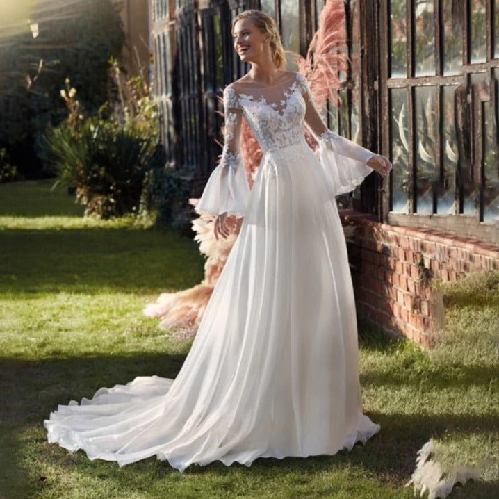 Experience the thrill and elegance of our Robe Henrietta! This trapeze-style wedding dress features a round neckline, floor-length hem, and gorgeous bishop sleeves. Walk down the aisle with confidence and grace in this stunning design.