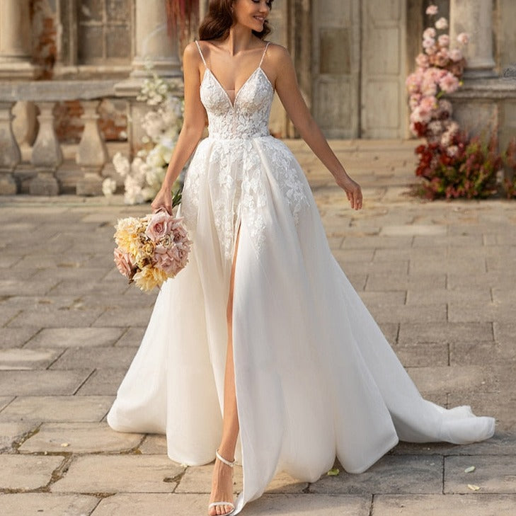 Indulge in luxury with the Robe Aneira. This deluxe, sleeveless wedding dress features a plunging v-neck and stunning appliques, invoking sensations of timeless elegance and sophistication. The open back adds a touch of sensuality, making it the perfect choice for the modern, stylish bride. Elevate your special day with this exquisite, high-end gown.