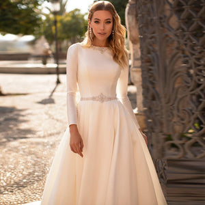 Wrap yourself in luxury with the Robe Mairead. Crafted with exquisite details, this custom satin robe features long sleeves and delicate pearl accents, perfect for any modest bride. Feel elegant and exclusive on your special day. Available in a variety of sizes to ensure the perfect fit.