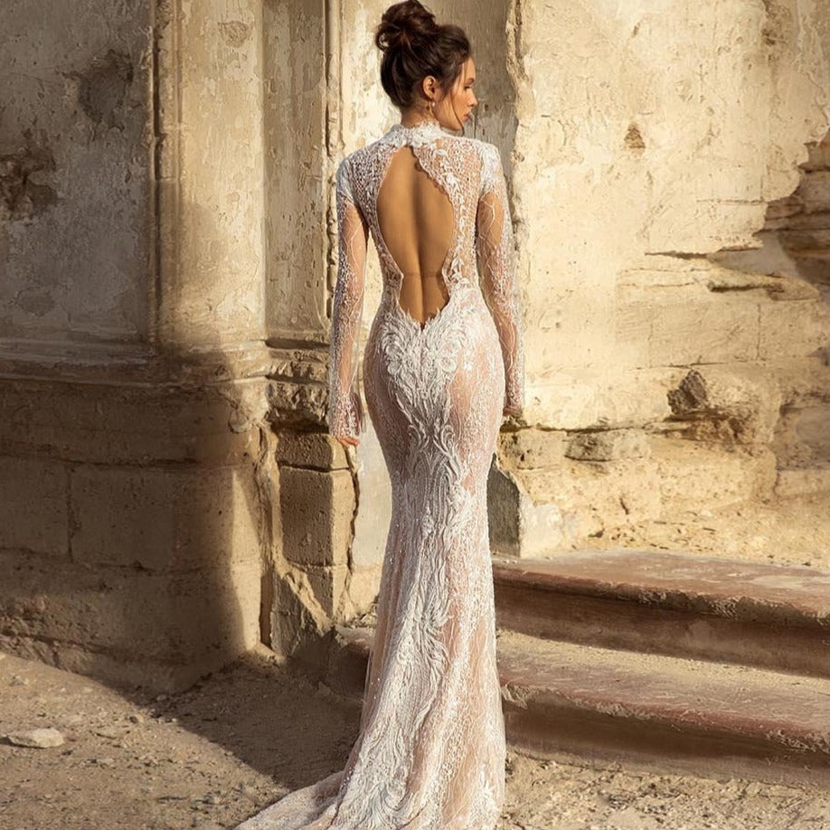 "The Robe Oriana is the perfect choice for any bride. With its elegant A-line silhouette, delicate spaghetti straps, and open back, this dress is both flattering and stylish. Made from high-quality drapé fabric, it flows beautifully to the floor, giving you a stunning, sophisticated look on your special day."