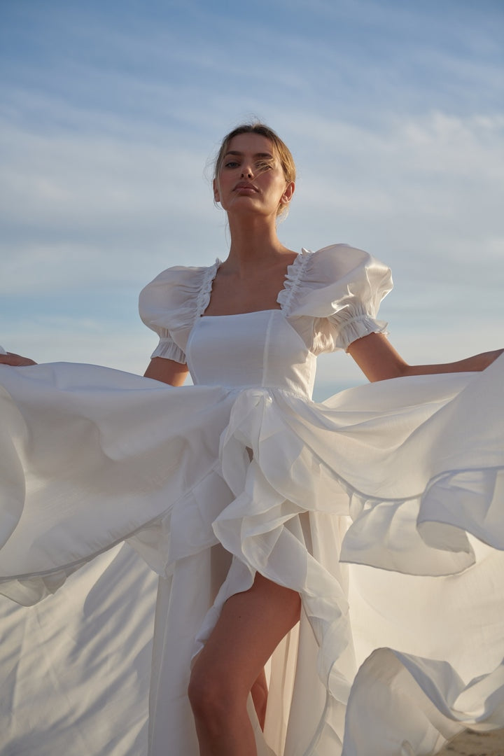 Introducing the Robe Eilidh, the perfect blend of elegance and sophistication. This white dress boasts a puffy silhouette, making it ideal for both bridal and evening wear. Transform any occasion into a memorable one with this stunning piece.