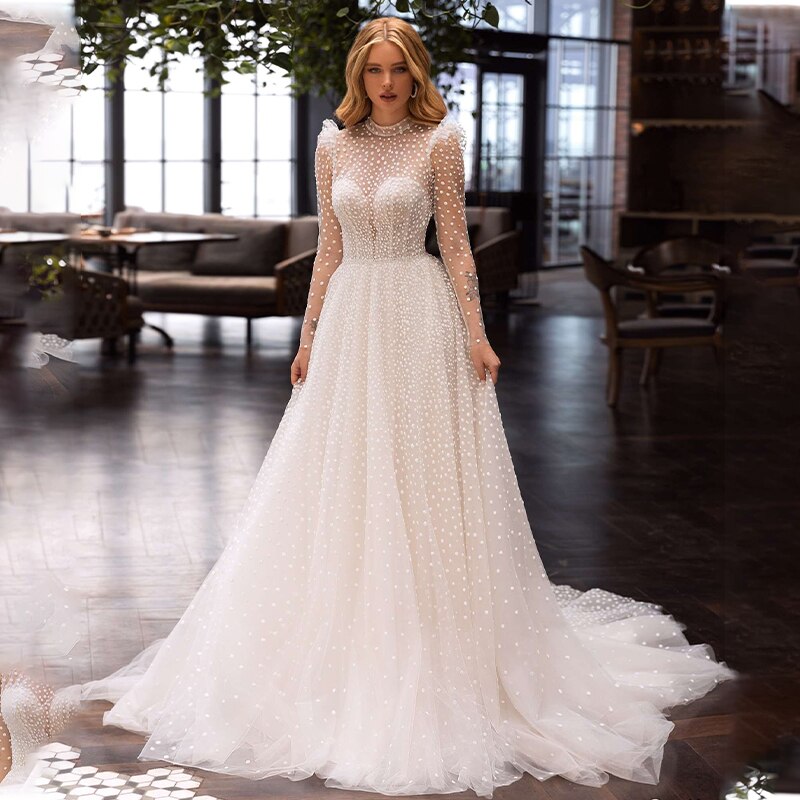 Indulge in the luxurious and bohemian style of Robe Matilda. With its long sleeves, high neck, and floor-length tulle, this wedding gown effortlessly exudes sophistication. Walk down the aisle with elegance and grace in this ethereal masterpiece.