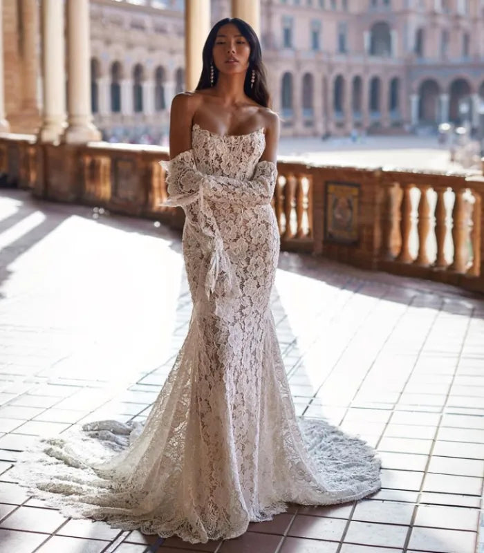 "Dare to make a statement on your special day with the Robe Rayna. This stunning lace illusion gown boasts a strapless, bare-shouldered design with a daring bow detail. Perfect for the risk-taker bride!"