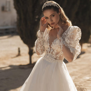 Indulge in elegant boho chic with Robe Ayline. This robe de mariage features a flattering V-neck and open back, with puffed sleeves for a touch of drama. The A-line silhouette adds a sexy yet sophisticated touch. Perfect for brides who want to make a statement on their special day.