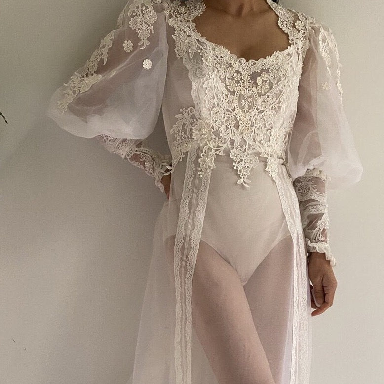 Wrap yourself in luxury and comfort with our Nightgown Addila. Made with delicate white lace and tailored to perfection, this robe-de-nuit will make you feel feminine and chic. With long sleeves and a gathered tulle design, it's the perfect addition to your bedtime routine. Treat yourself to a good night's sleep in style.