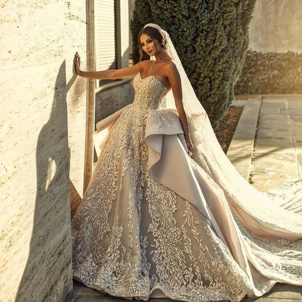 Indulge in elegance with the Robe Livana. Made of intricate lace from Dubai, this stunning bridal robe features a cathedral train for a dramatic effect. Make your big day unforgettable and feel like a goddess in the Robe Livana.