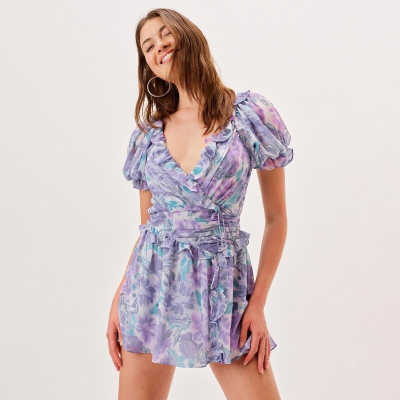 The Robe Ila is a must-have for any fashion-forward individual. Made of recycled poly, this watercolor floral chiffon mini dress is a true work of art. With its cascading ruffle detailing, flattering crossover bodice, and figure-flattering gathered skirt with side slit, this dress exudes elegance and sophistication. Features such as a pretty back keyhole and puff sleeves add the perfect touch of femininity. Elevate your wardrobe with the Robe Ila.