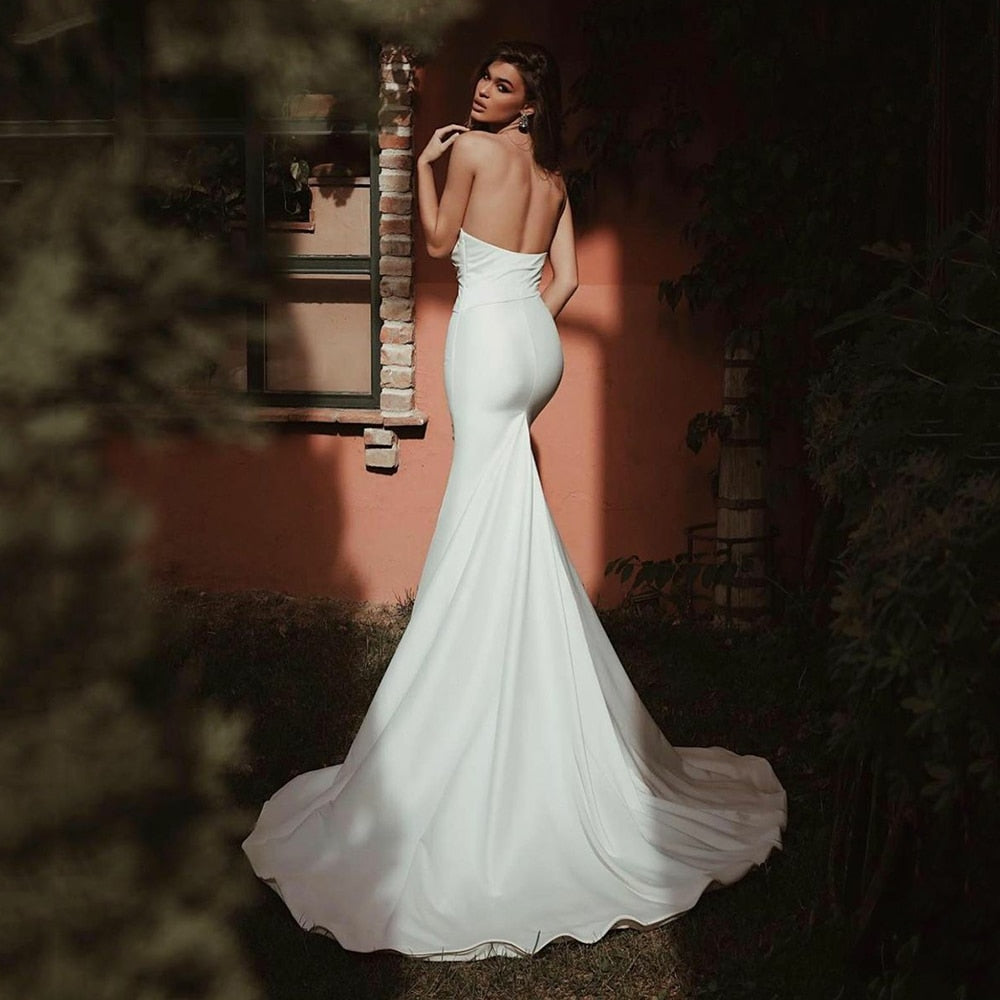 Get ready to stun on your special day with the Robe Indy! This satin mermaid wedding dress features a strapless design and a chic, backless style that will turn heads. The trumpet silhouette flatters every figure, making you feel confident and sexy as you walk down the aisle. Elevate your bridal look with this beautiful and elegant gown.