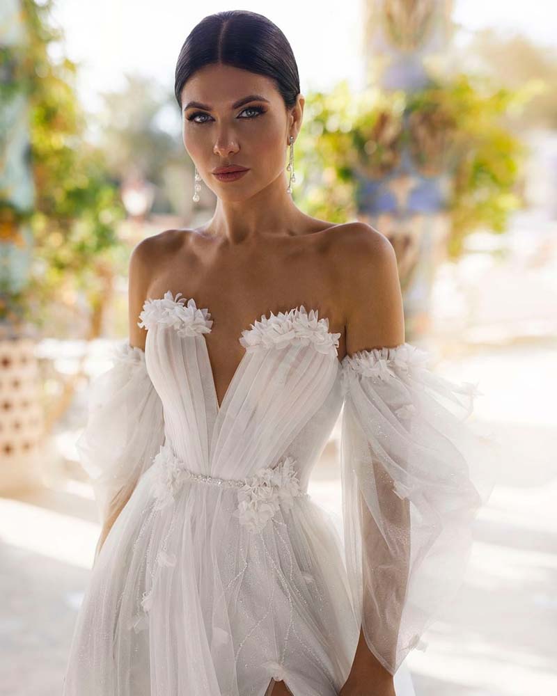 Designed for a princess bride, the Robe Araminta is a stunning white tulle dress with billowing puff sleeves and a seductive high leg slit. Its intricate appliques and sweetheart neckline add a touch of elegance to this sexy and modern design. Perfect for making a statement on your big day.